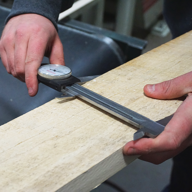 A Highland Hardwoods woodworker measures the width of a board.