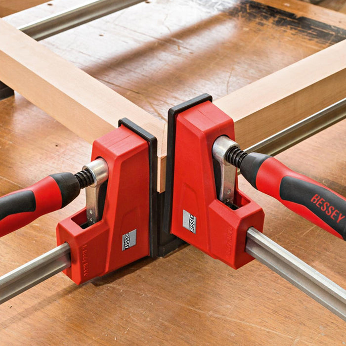 Two Bessey bar clamps being used to join two pieces of wood.