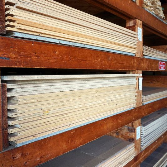Sheets of plywood stacked on warehouse shelving.